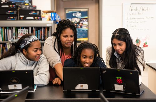 A female 女王调教免费专区视频 educator with three female students at laptops in a classroom.