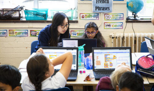 特黄做受又硬又粗又大视频 classroom with woman teacher and young students at laptops doing Scratch coding.