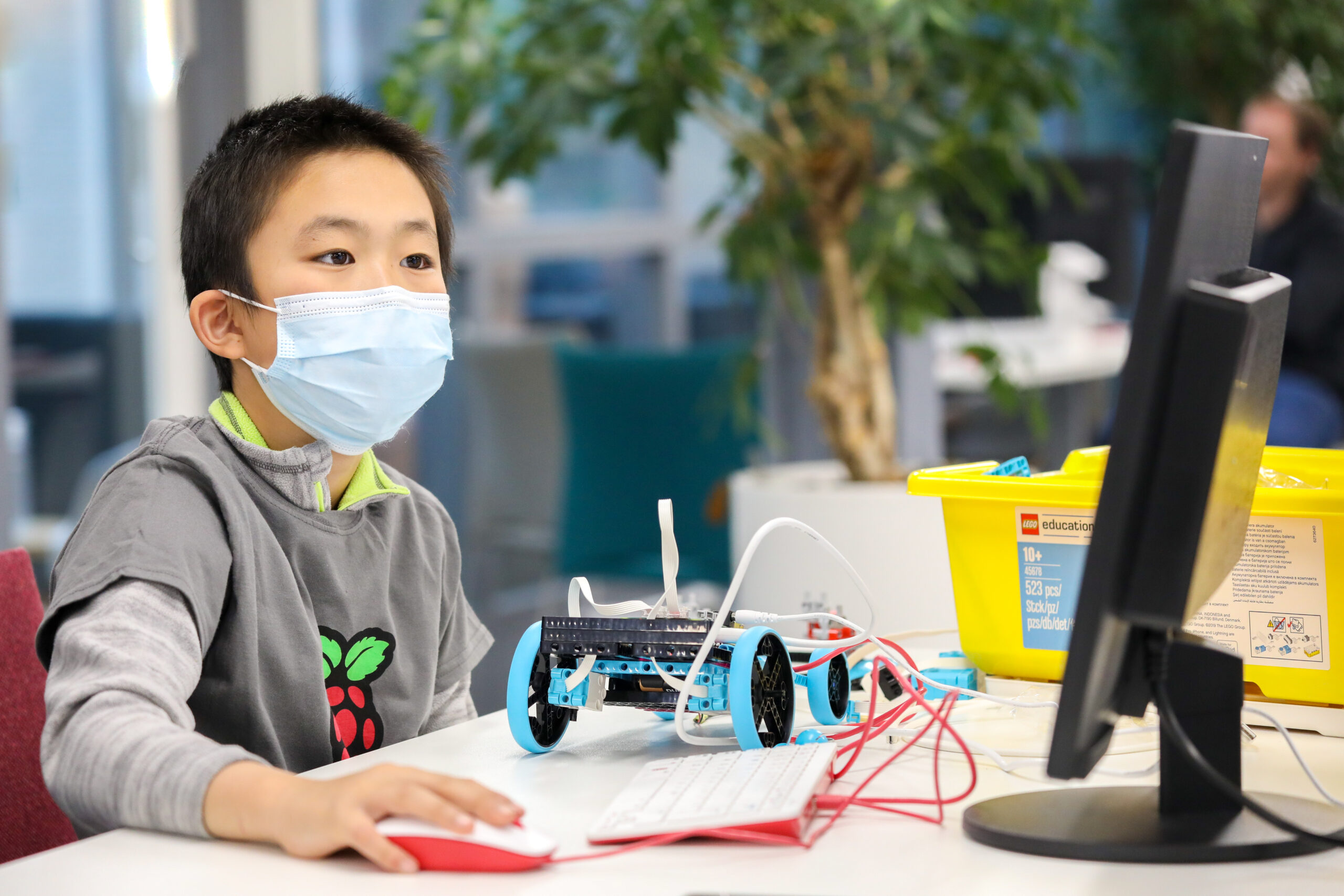 A young person builds a robot buggy with LEGO bricks and the wwwxxx Pi Build HAT.