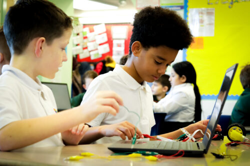 Two learners do physical 舞蹈室边跳舞边做h in the primary school classroom.