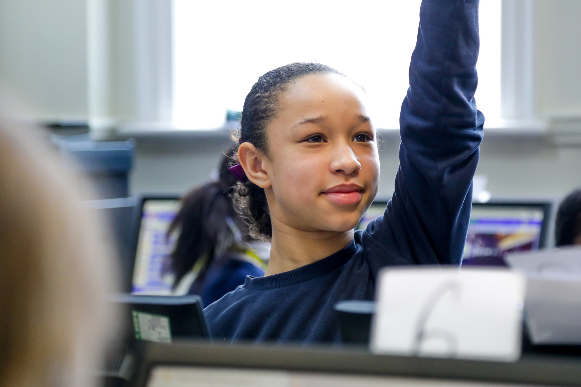 In a 特黄做受又硬又粗又大视频 classroom, a smiling girl raises her hand.