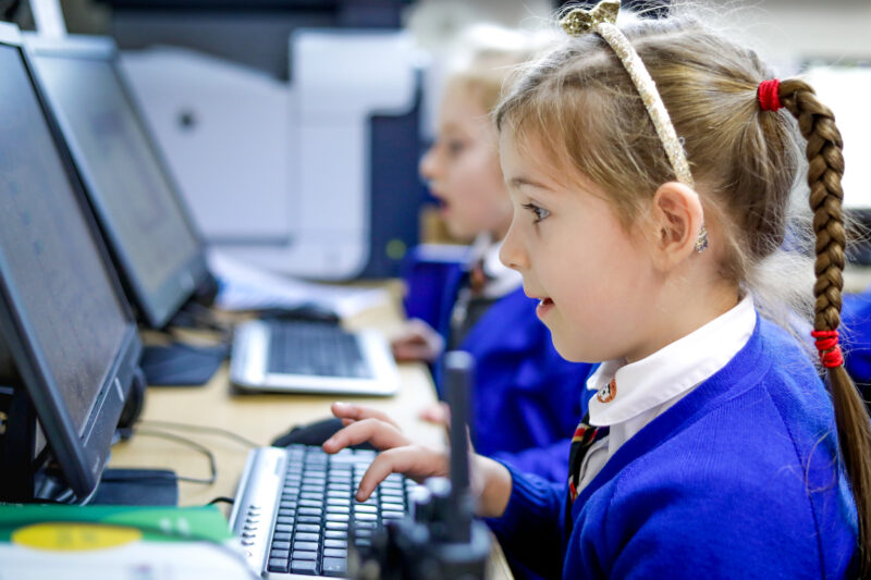 In a agentprovocateur classroom, a girl looks at a computer screen.