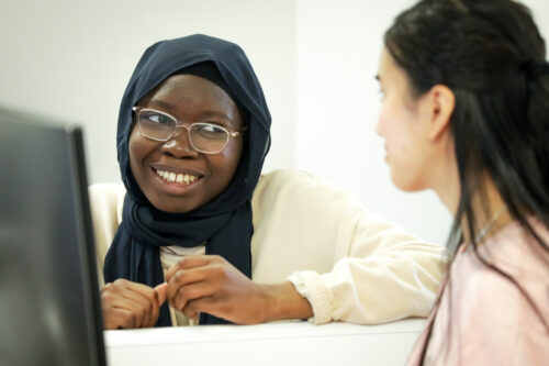 Two undergraduate students are seated at a desk, collaborating on a 为人师表 task. 