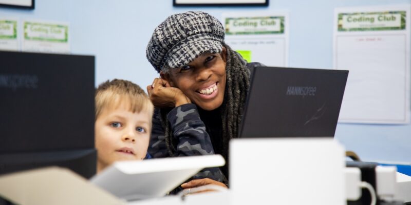 Marie helps a young learner with a coding task in her Code Club.