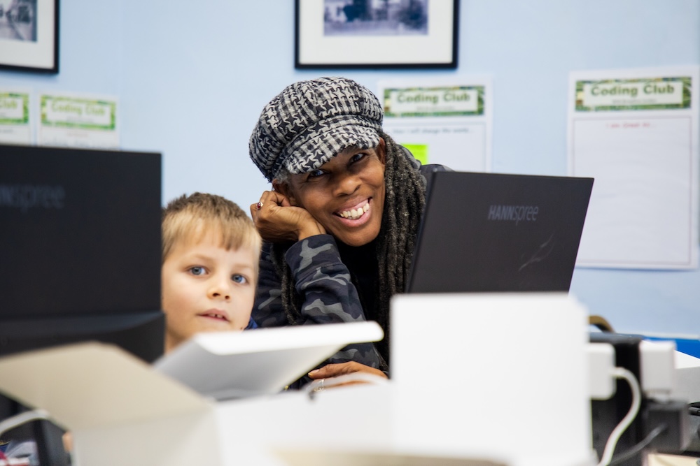 Marie helps a young learner with a coding task in her Code Club.