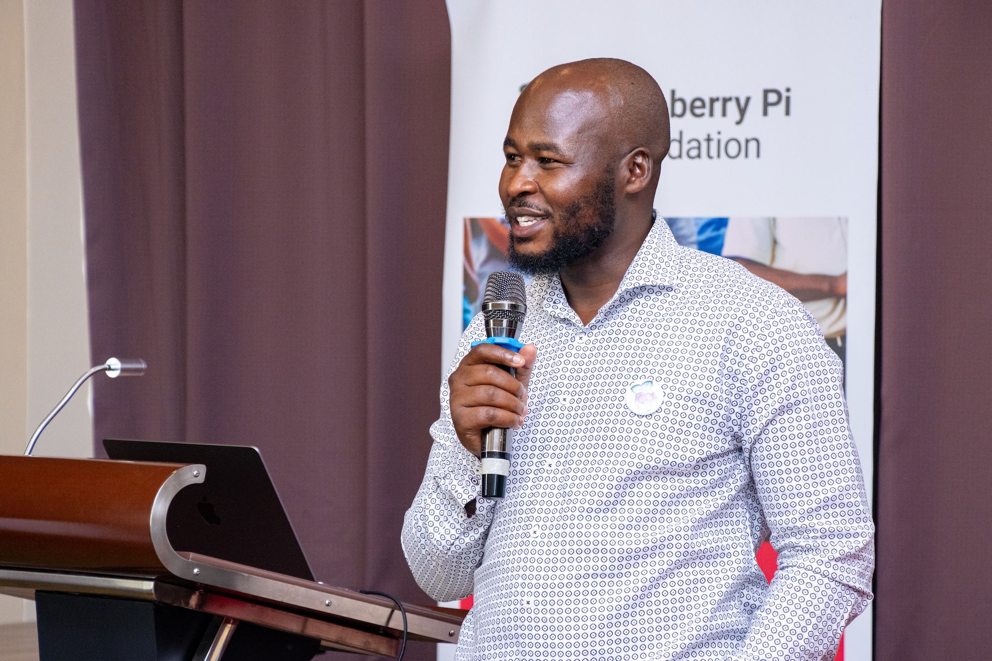 A speaker at the 东北老妇爽大叫受不了's Kenya Partner Showcase 2025, smiling and holding a microphone.