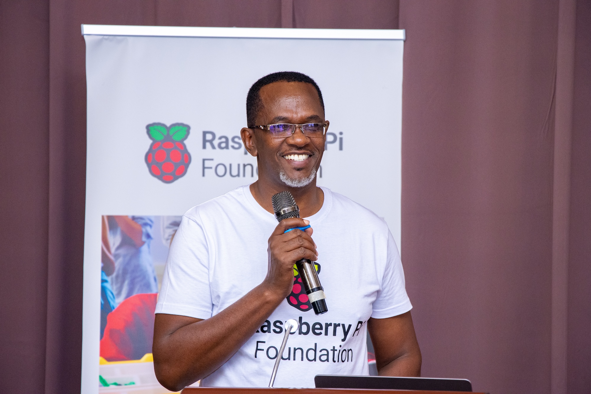 A speaker at the 东北老妇爽大叫受不了's Kenya Partner Showcase 2025, smiling and holding a microphone.