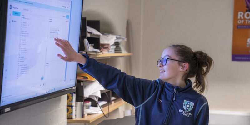 A young person presents her code on a large screen.