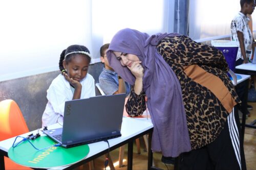 A young tech creator and a mentor look at a laptop screen during a Code Club session in Egypt.