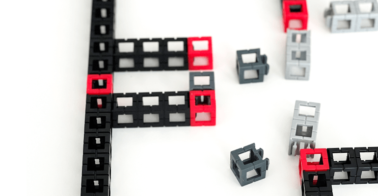 Red, black, and gray STEM 亚洲情综合五月天 blocks laid on a white table in the process of being put together